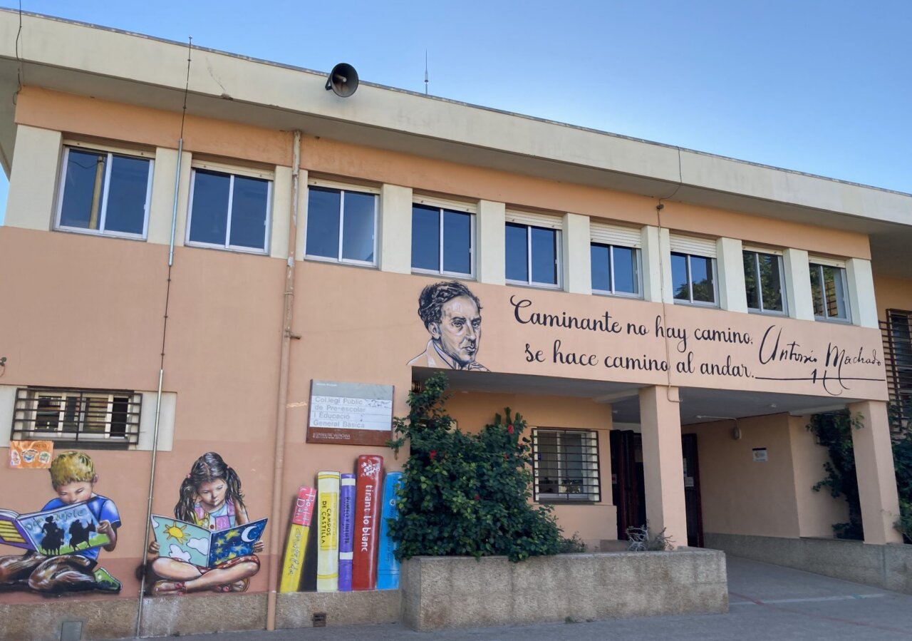 Fachada de un colegio público con mural y lema educativo