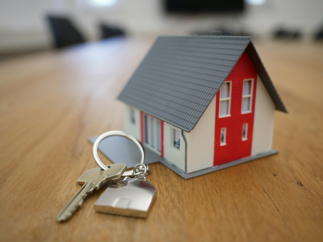 Modelo de casa y llaves Modelo de casa con llaves sobre una mesa de madera